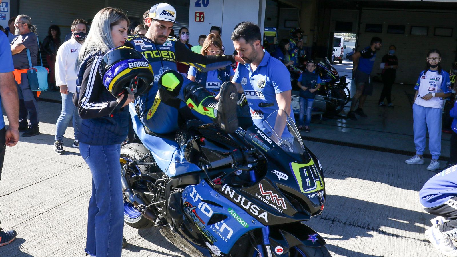 Un piloto de la Copa Handy, ayudado para subir a la moto.