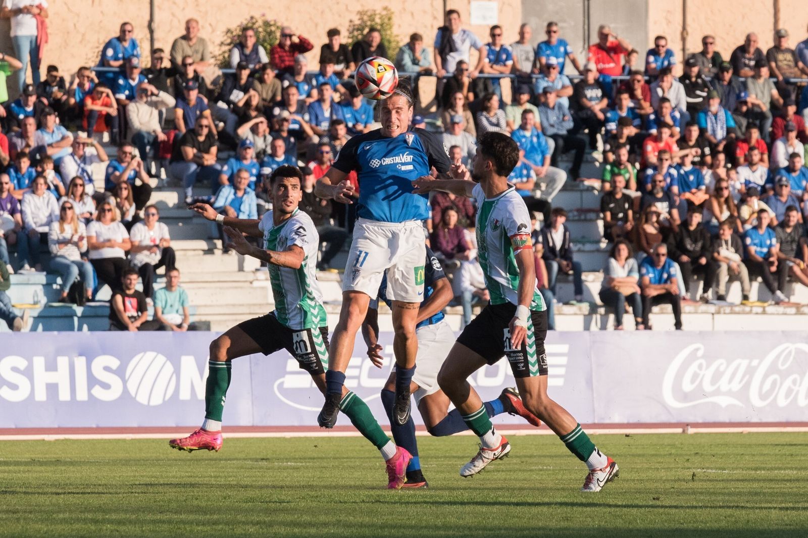 El delantero azulino Aquino conecta con el balón de cabeza entre dos rivales.