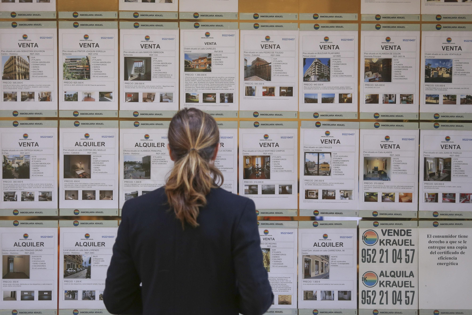 Una mujer observa las ofertas de pisos en una inmobiliaria. Una mujer observa las ofertas de pisos en una inmobiliaria.