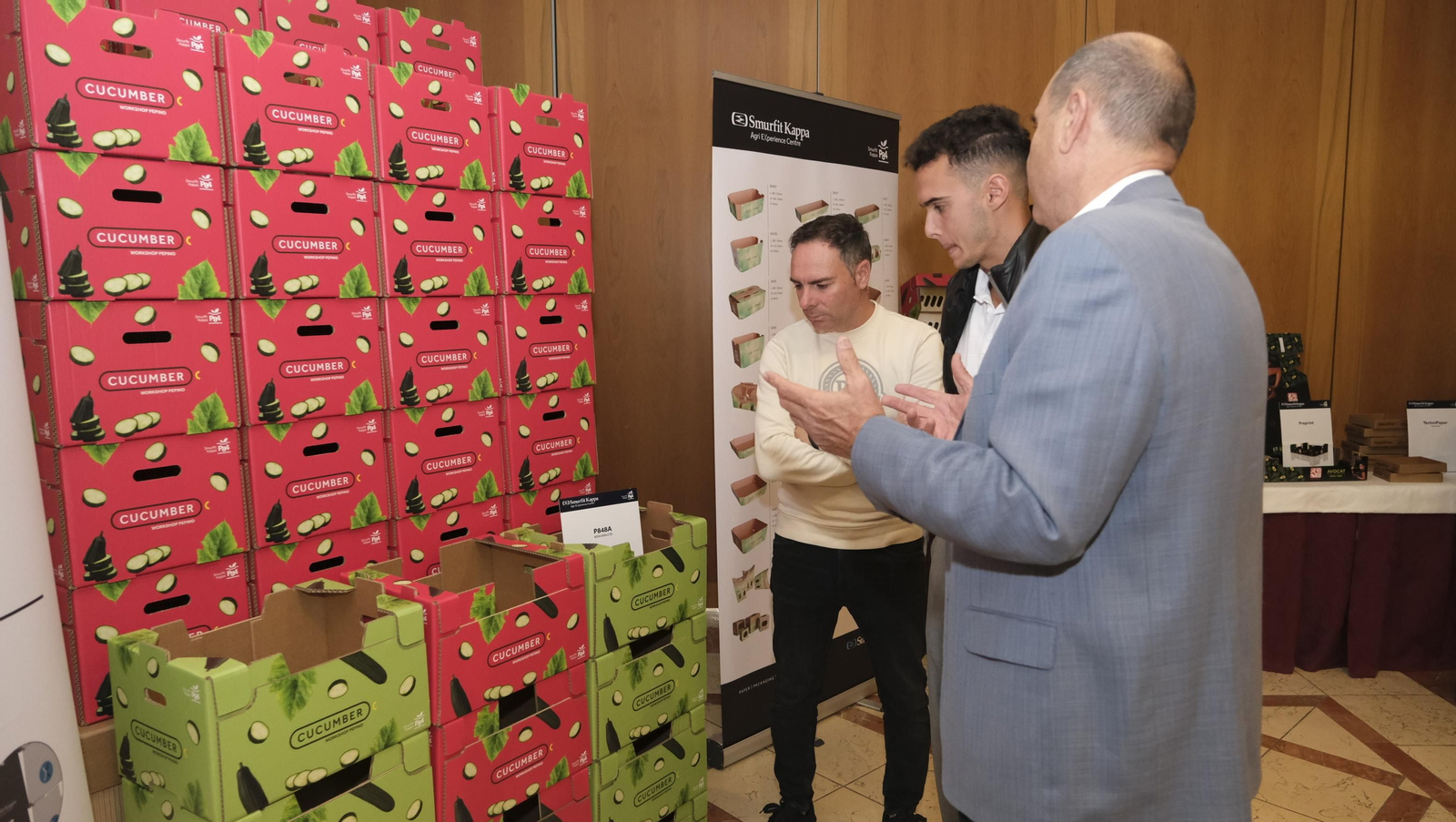 Encuentro de productores del pepino observando la exposición de embalajes de cartón reciclado.