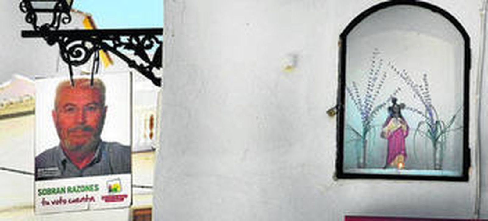 Un cartel electoral del candidato de IU comparte espacio con una imagen del Sagrado Corazón.