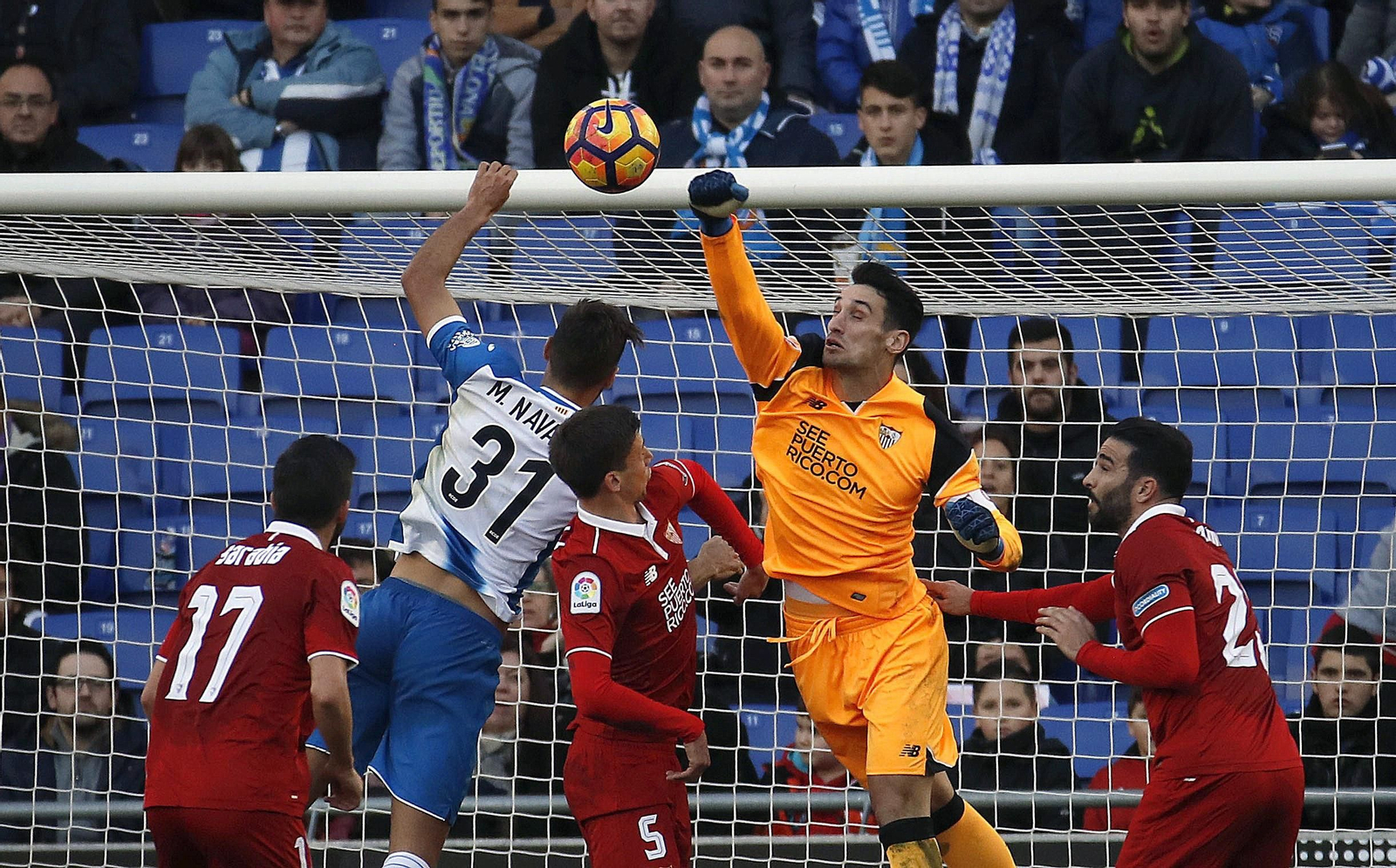 Sergio Rico despeja de puños ante Lenglet y Rami.