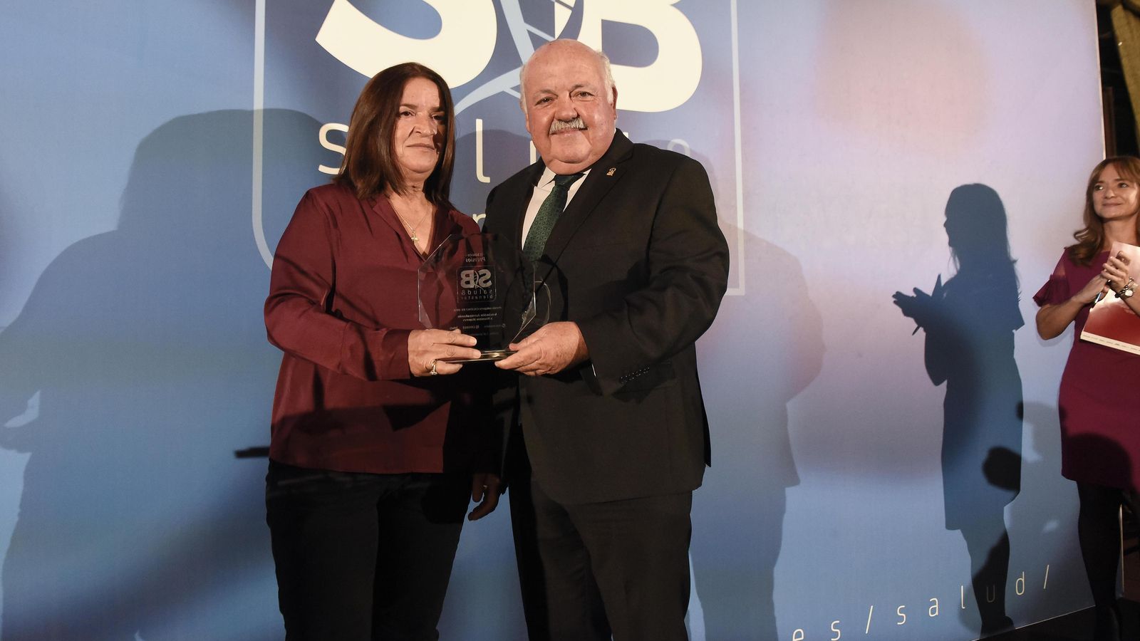 Isabel Gonález recibe dle premio de la mano de Jesús Aguirre, consejero de Salud.