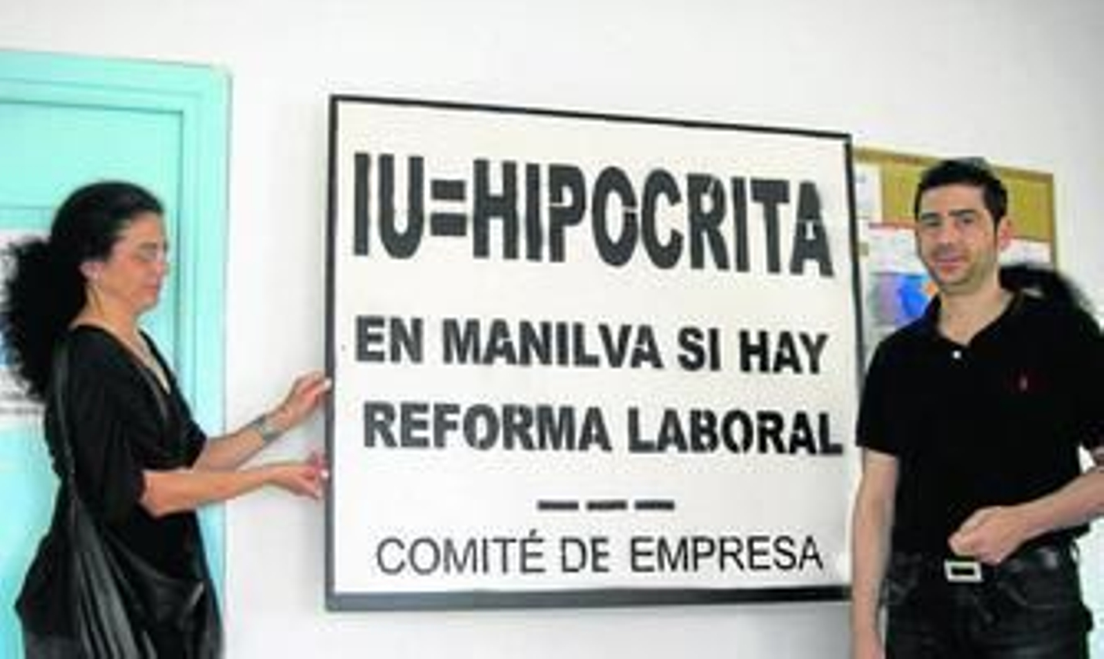 Dos líderes sindicales transportan el cartel que la alcaldesa les obligó a retirar de la fachada de la sede del comité de empresa.