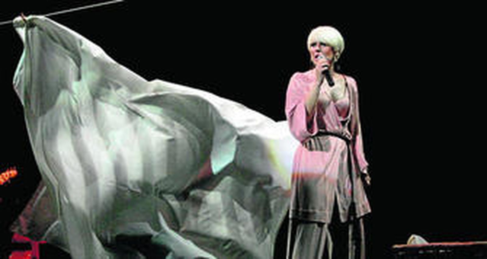 Pasión Vega deja caer una de las sábanas colgadas en el escenario mientras canta.