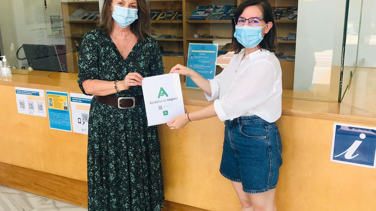 La edil Luisa Barranco, a la izquierda, muestra el sello de la Oficina de Turismo.