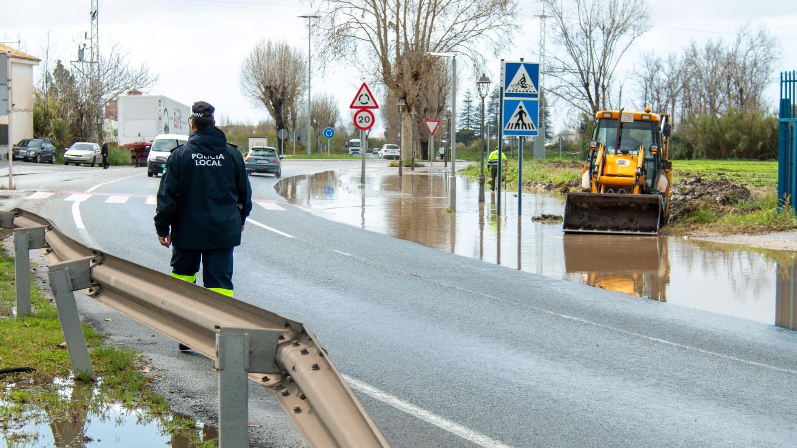 Un Policia Local de Motril controla el tráfico mientras un operario municipal achica agua en la bajada de la playa