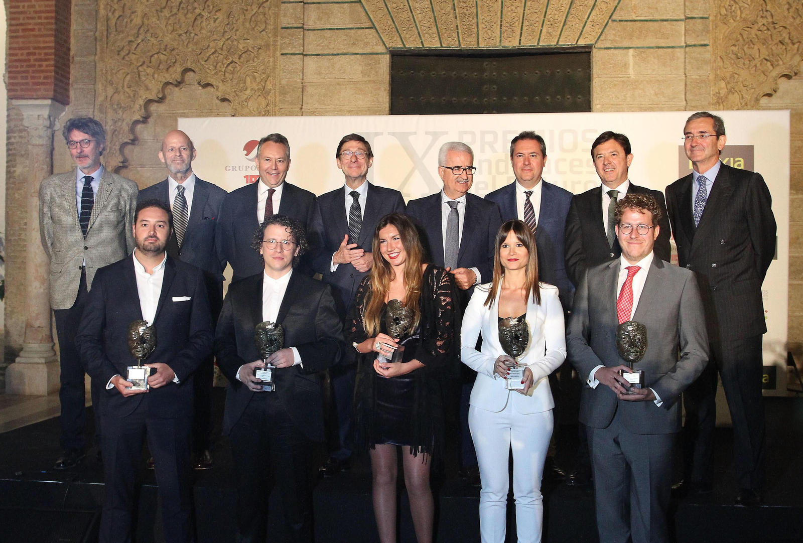 Arriba, José Ignacio Rufino, doctor en Economía y secretario del jurado; José Antonio 'Anchoa' Muñoz, gestor deportivo y vocal de Deportes en el jurado; José Joly, presidente de Grupo Joly; José Ignacio Goirigolzarri, presidente de Bankia; Manuel Jiménez Barrios, vicepresidente de la Junta de Andalucía; Juan Espadas, alcalde de Sevilla; Joaquín Holgado, director territorial de Bankia en Andalucía, Extremadura y Castilla-La Mancha; y Antonio Fragero, presidente del patronato de la Fundación CES Proyecto Hombre y vocal de Acción Social en el jurado; debajo, los premiados: Juan José Artero (Empresa); Alberto Martos (Cultura); Paula Ruiz (Deportes); Marta Medina (Acción Social) y Guillermo Mínguez (Ciencia).
