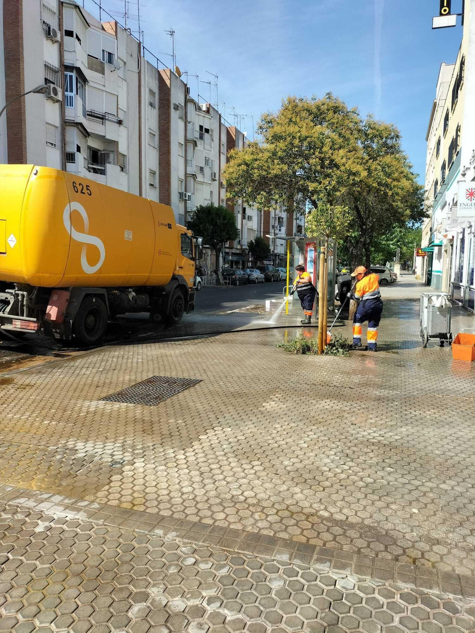 Dos operarios de Lipasam baldean una acera.