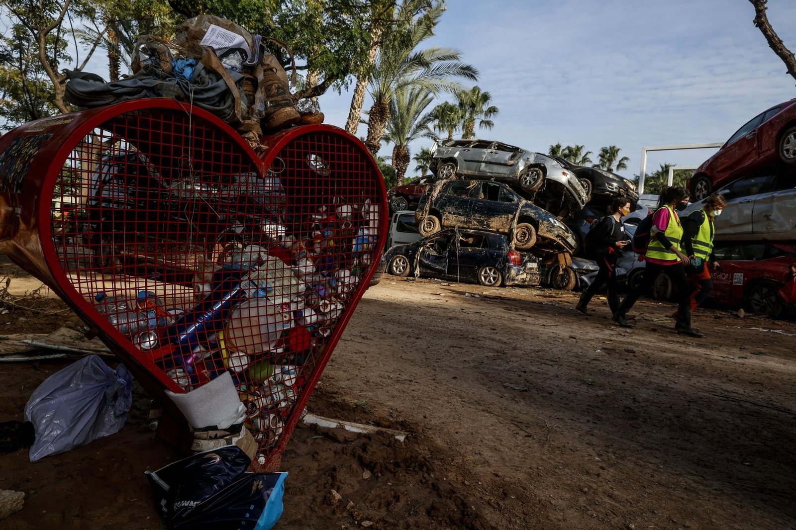 Un grupo de mujeres pasa junto a un grupo de coches amontonados en Sedaví.