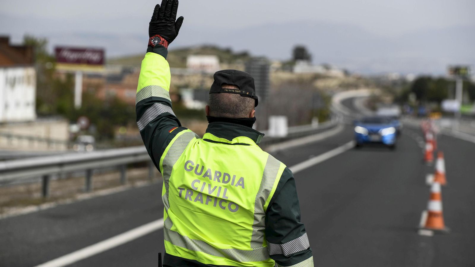 Un guardia civil da el alto para que se pare un vehículo en un control.