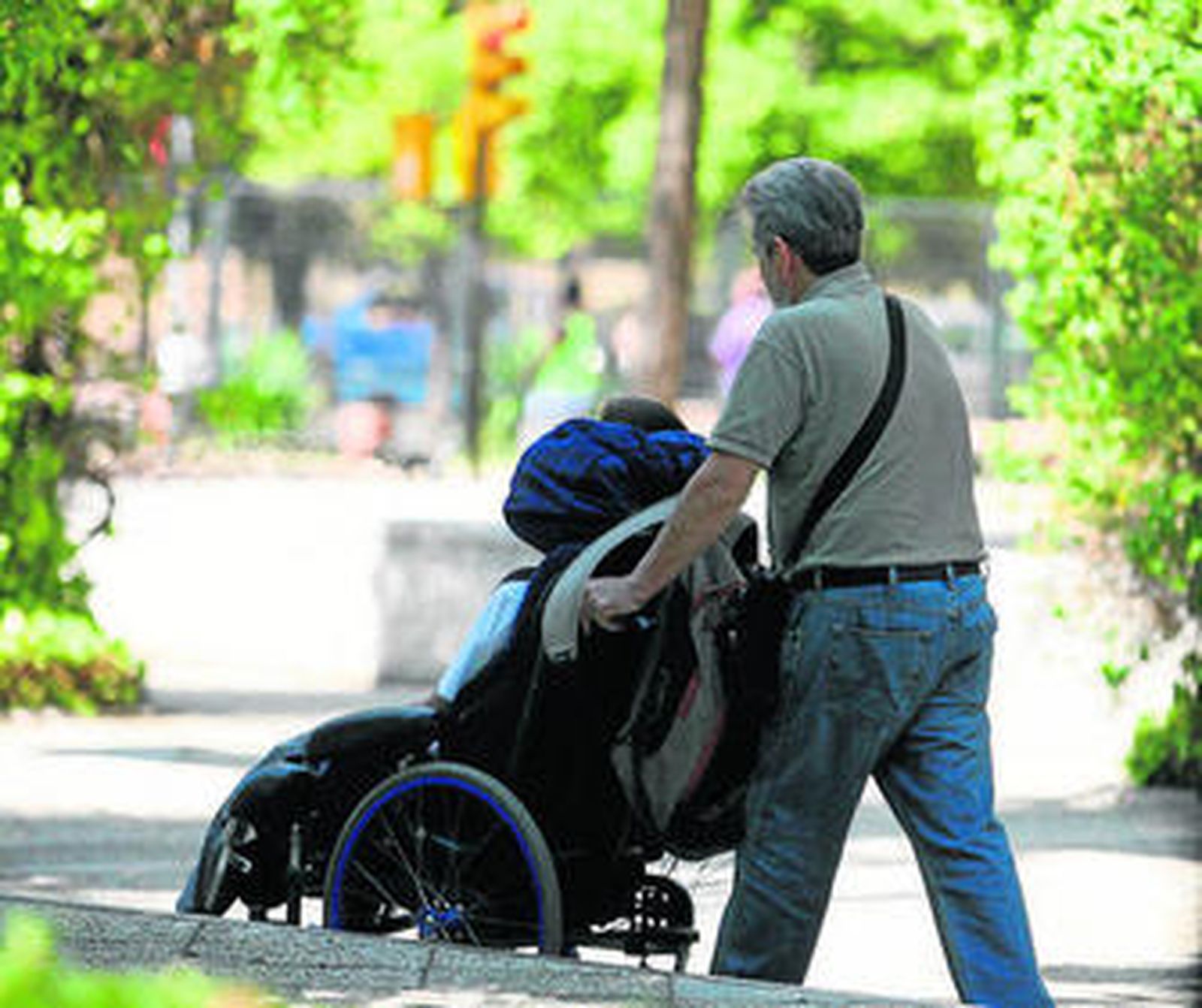 Un hombre empuja a una persona en una silla de ruedas.