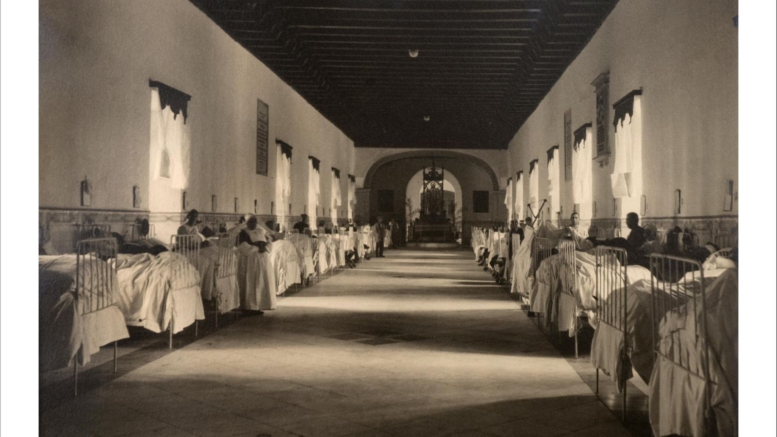 Enfermos en sus camas junto a familiares en una de las grandes habitacioones compartidas del Hospital de las Cinco Llagas.