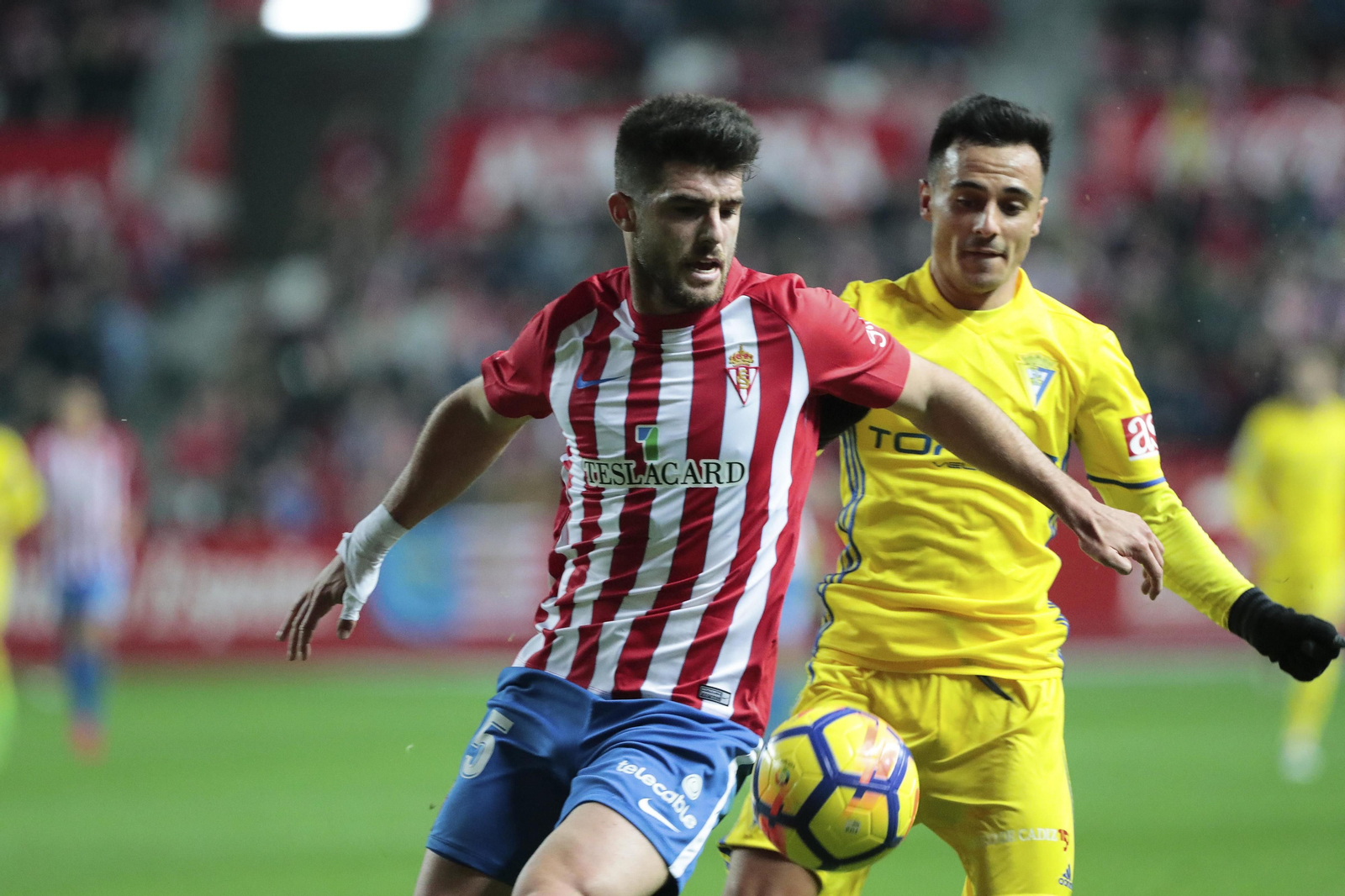 Álvaro García trata de llegar al balón, protegido por Jordi Calavera, en una acción del partido disputado en El Molinón.