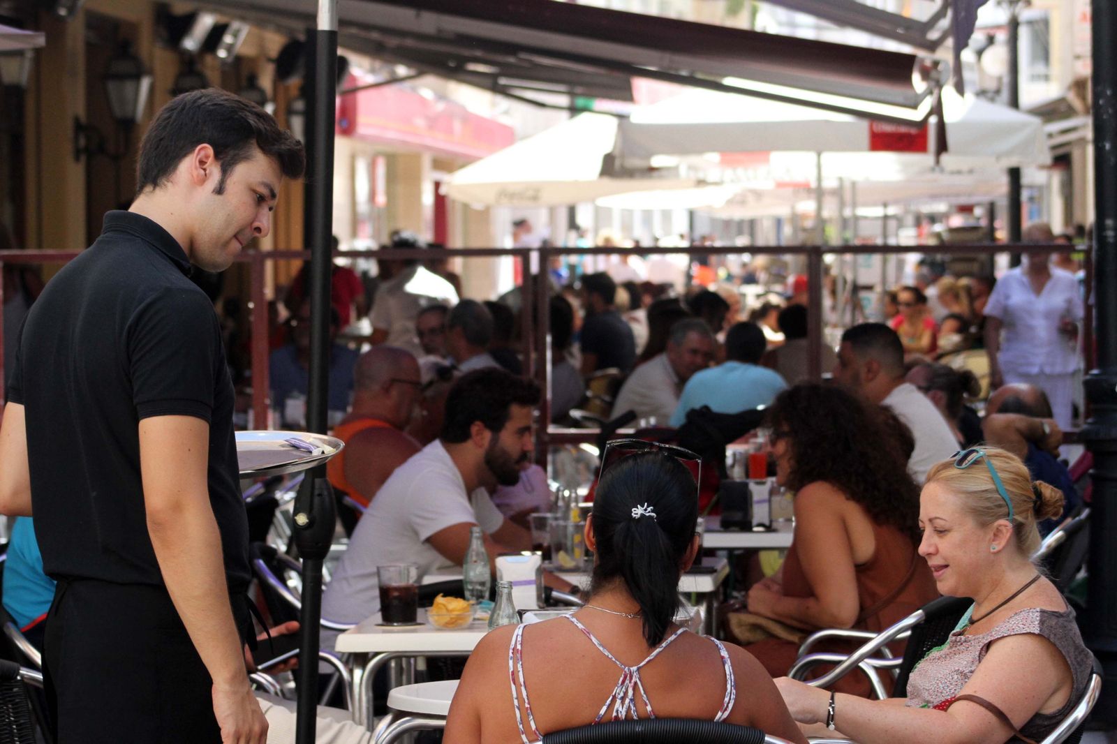 Un camarero atiende a dos turistas.