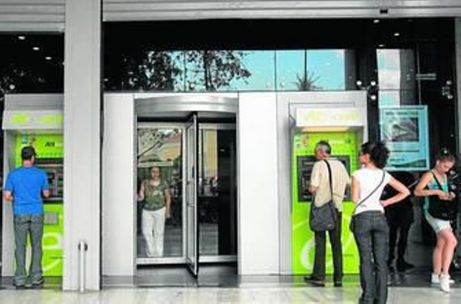 Varios clientes retiran dinero del cajero automático en Atenas.