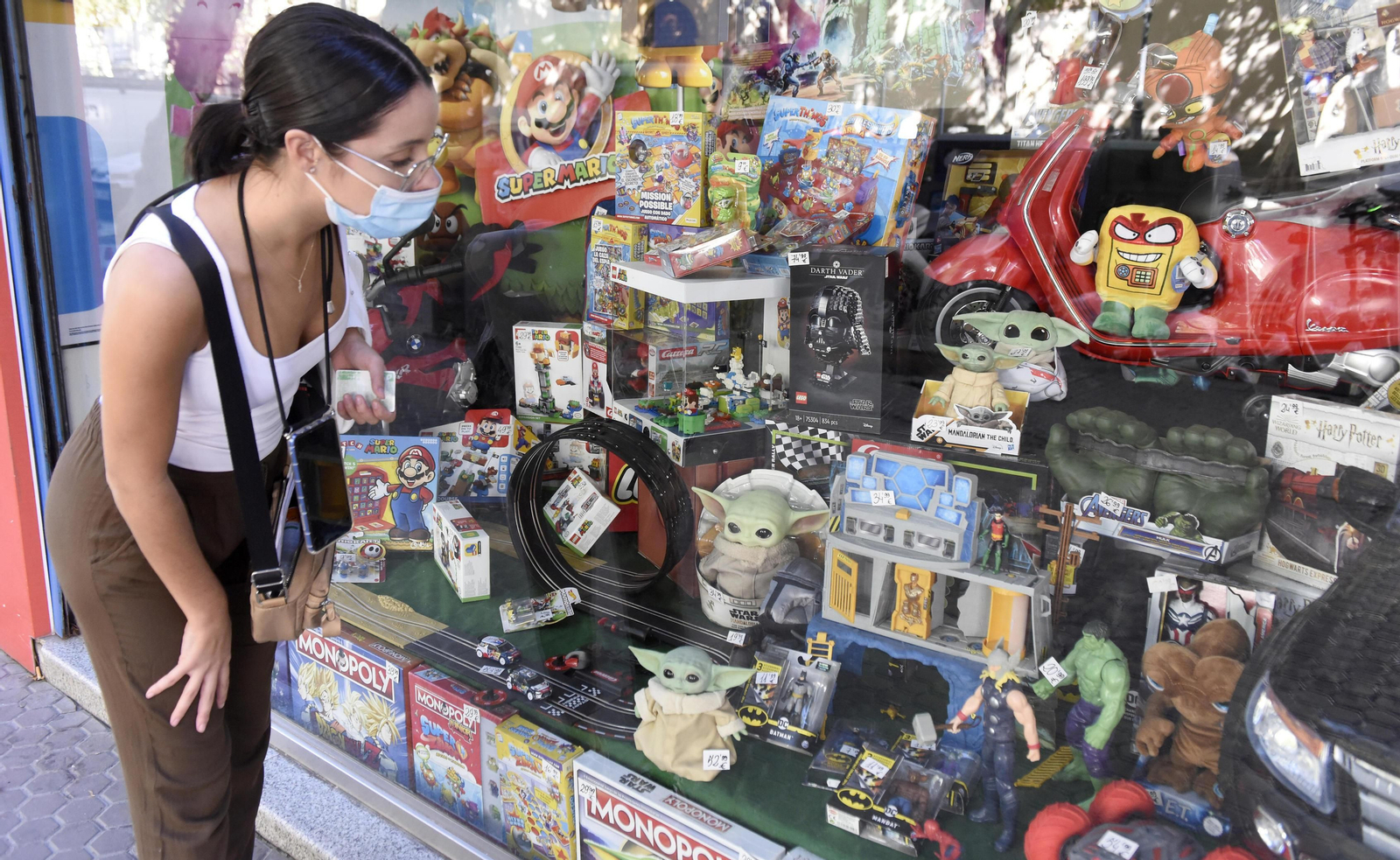 Una joven observa el escaparate de una juguetería.