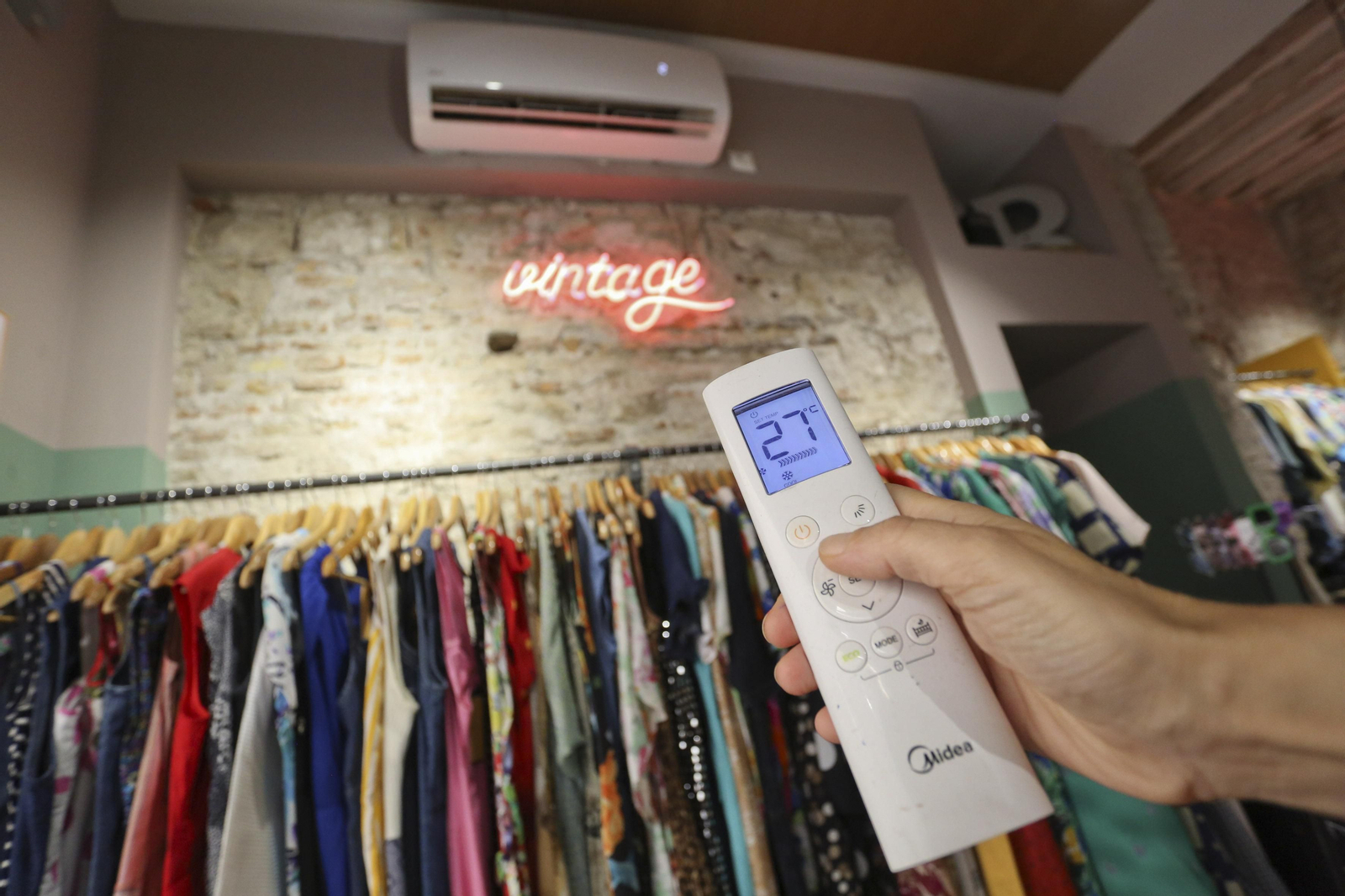 Una trabajadora de una tienda pone el aire a 27 grados.