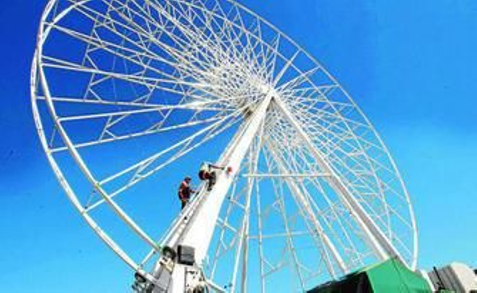 Dos feriantes trabajan ayer en el siempre complicado montaje de la noria, una de las señas de la Feria.