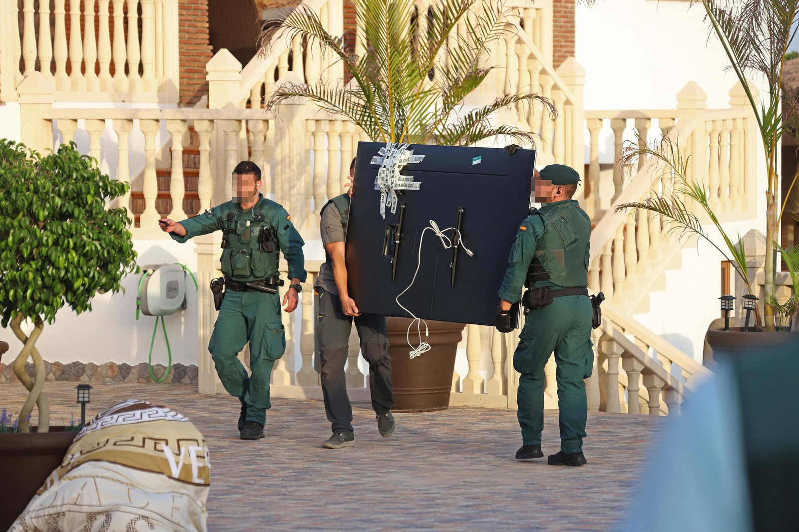Dos guardias civiles cargan un con televisor de gran tamaño decomisado en una operación contra el tráfico de drogas.