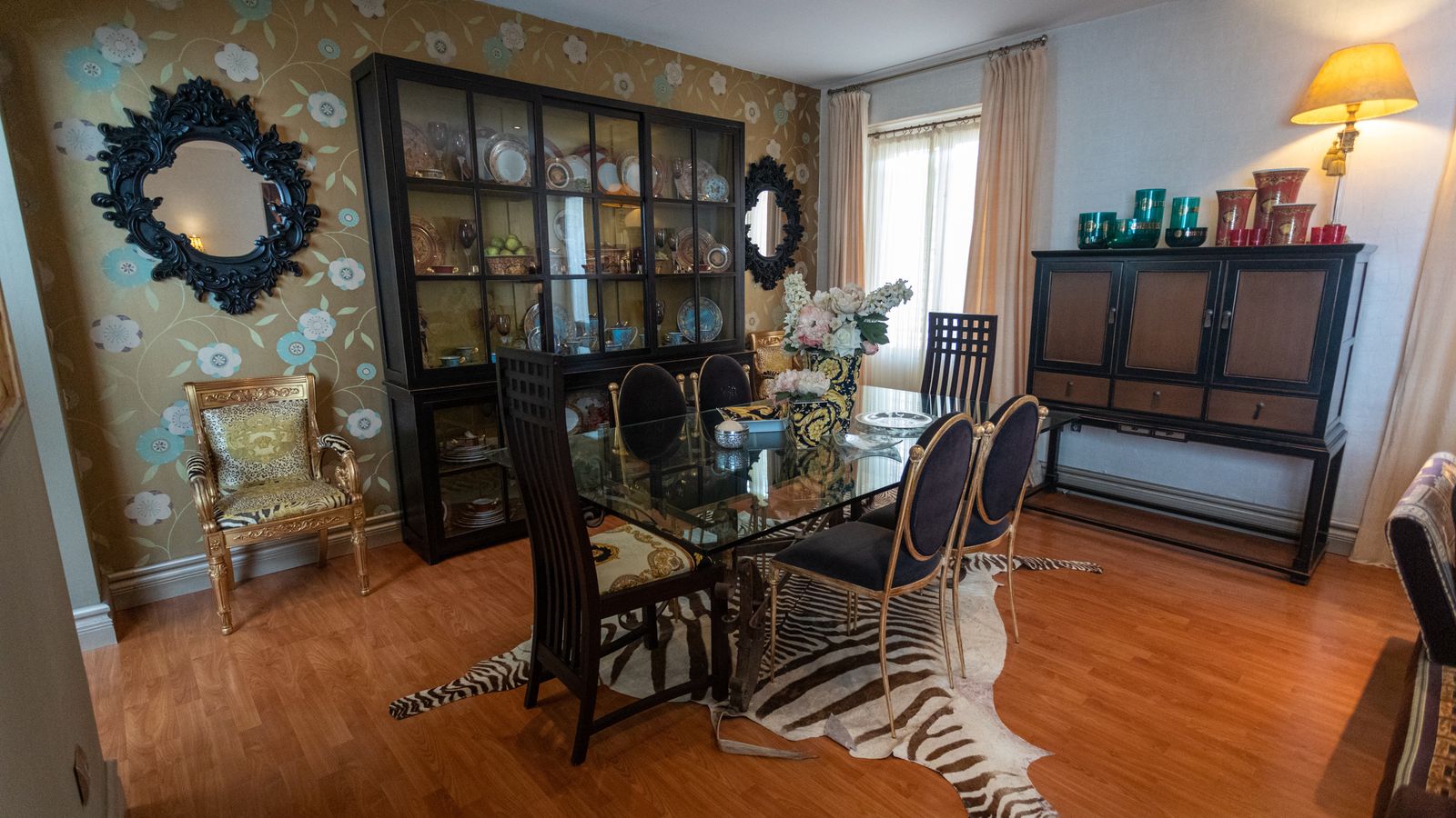 Comedor. Mesa de hierro forjado y cristal junto a cuatro sillas de hierro acabadas en dorados y otras dos lacadas en negro.