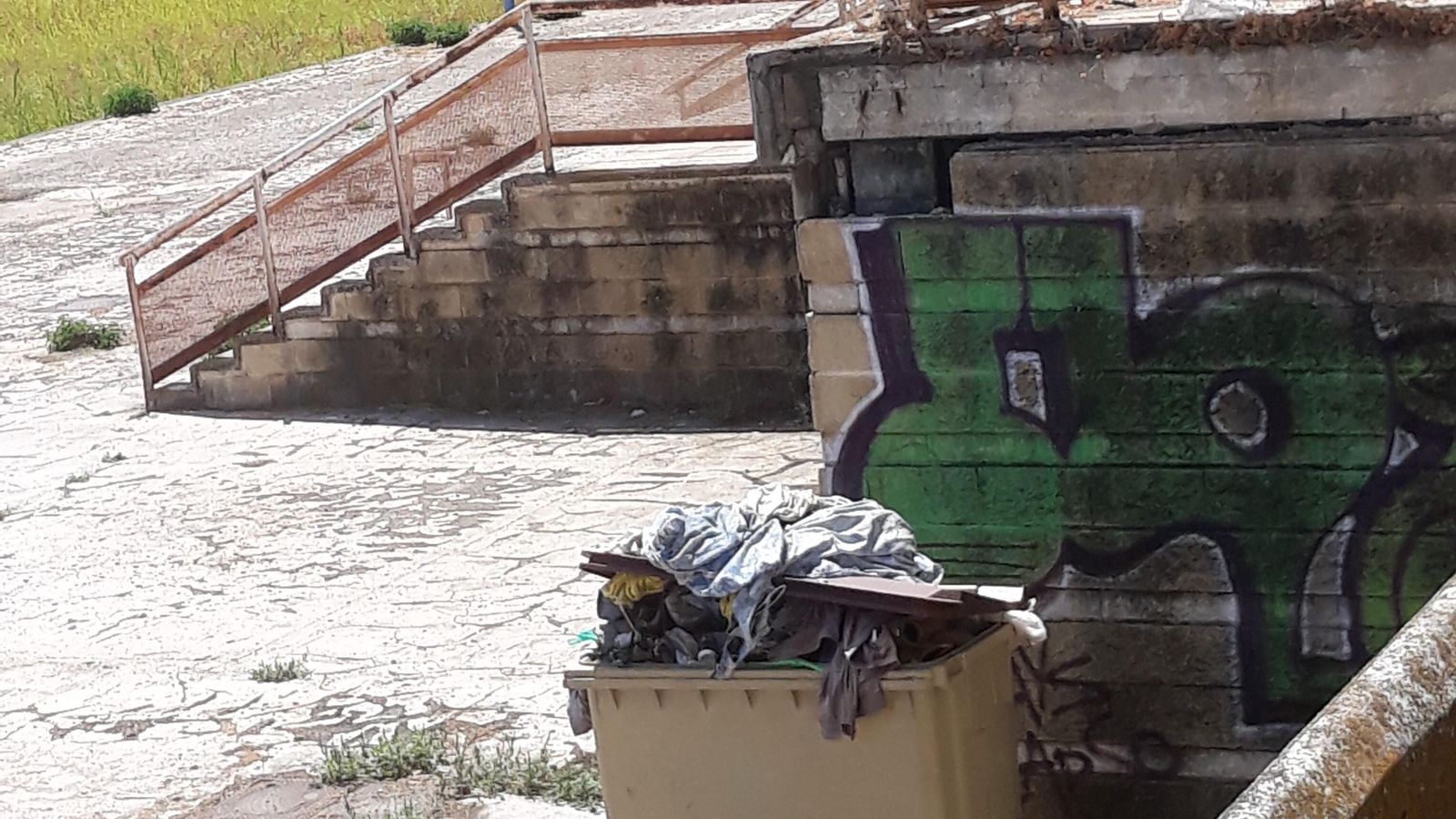 Ropa tirada en un contenedor junto a la caseta ocupada.