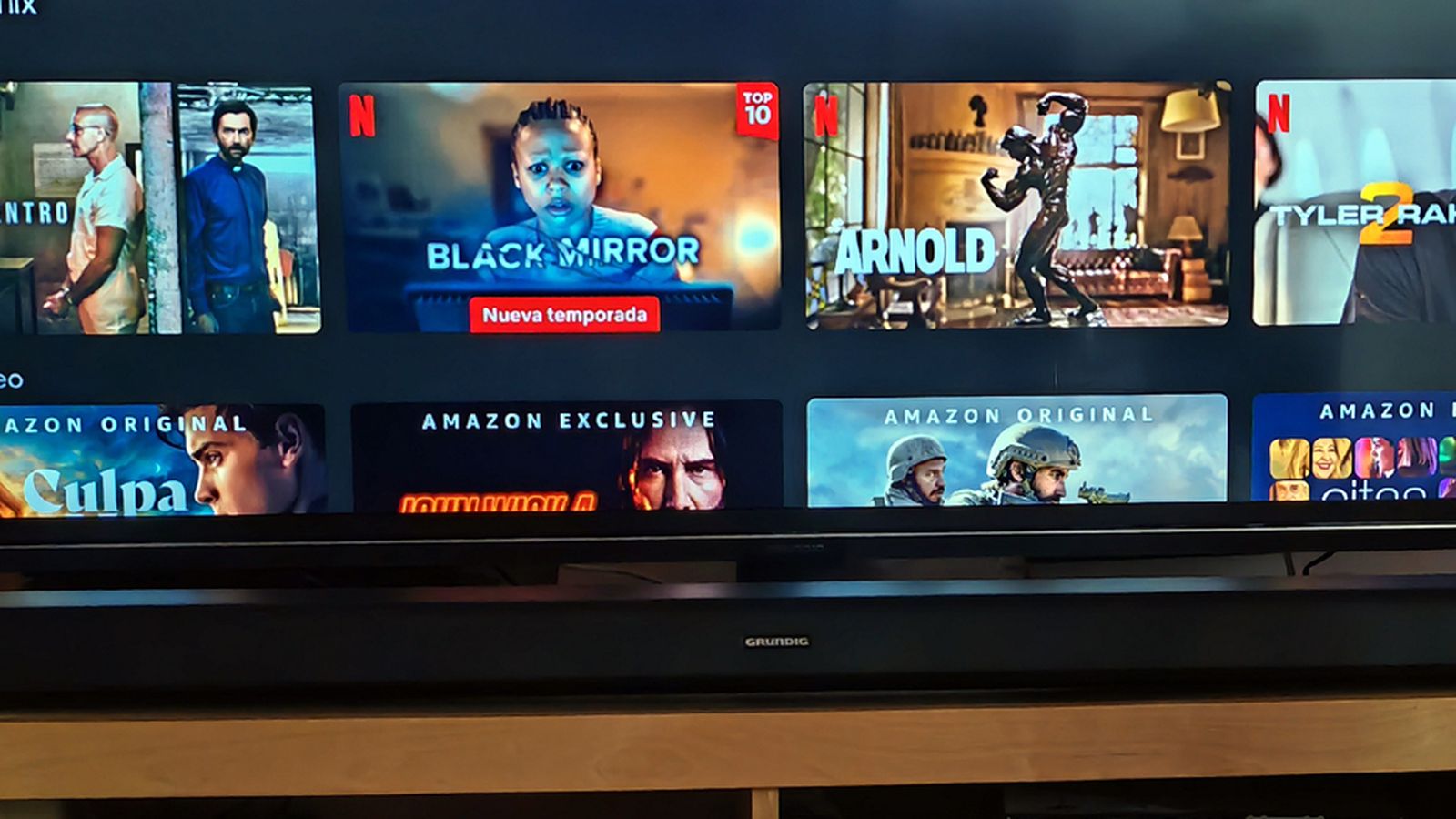 Barra de sonido Grundig con subwoofer integrado GSB 910 S, instalada bajo un televisor también Grundig