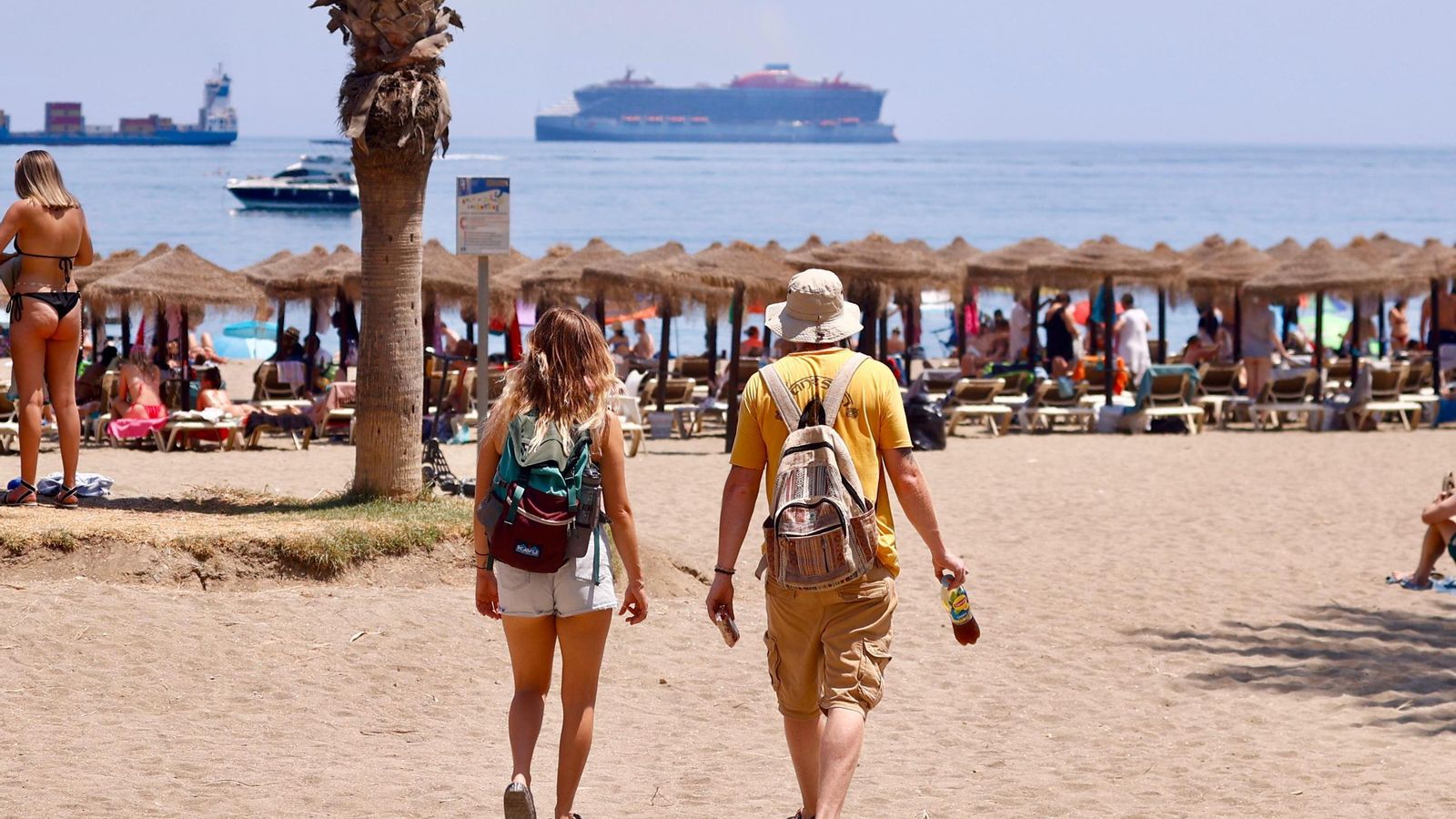 Dos personas llegando a la playa de La Malagueta.