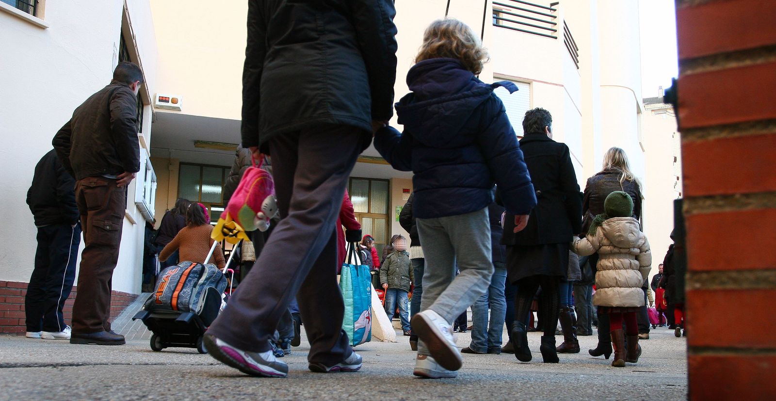Varios niños en las puertas de un colegio.