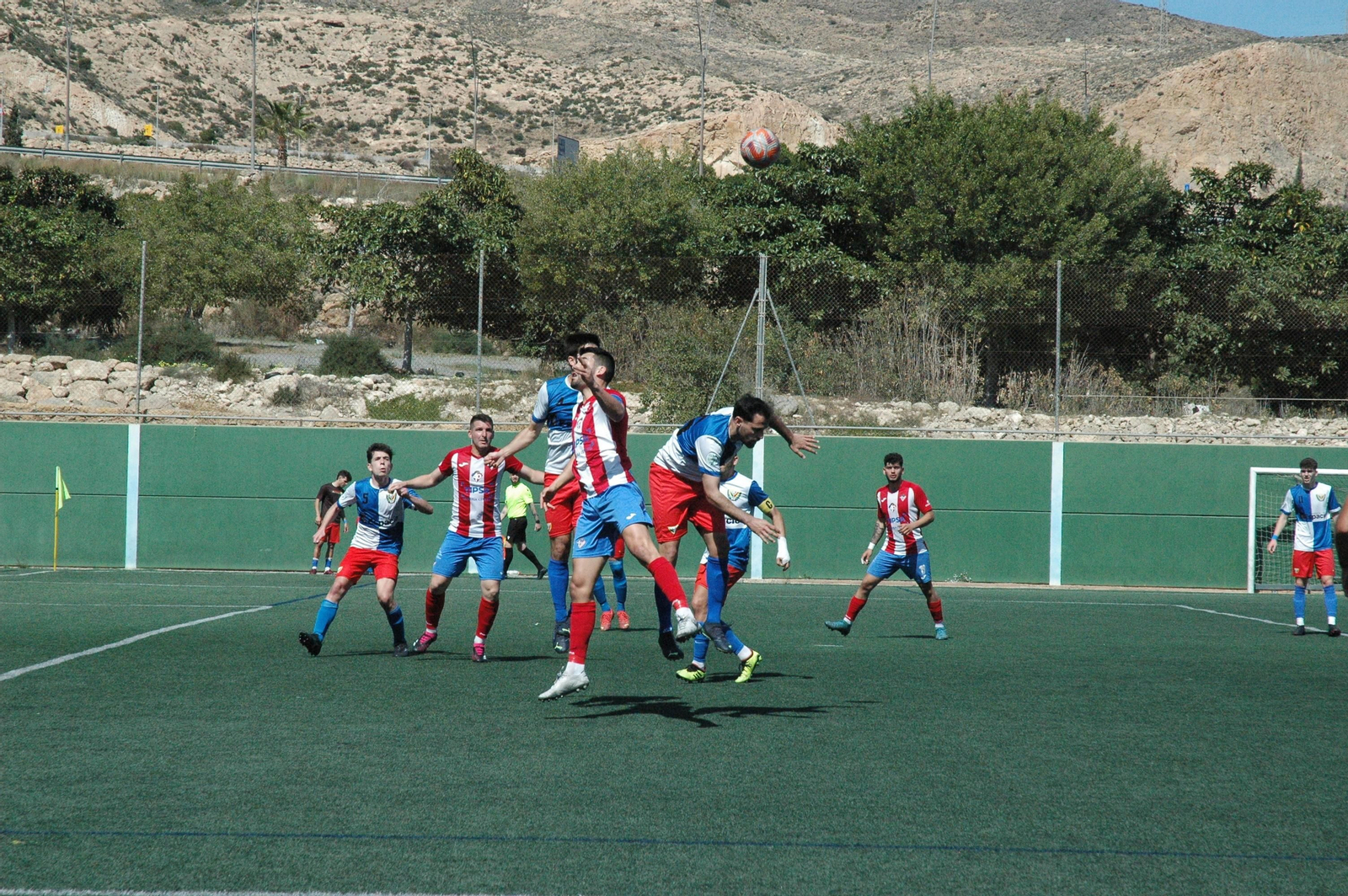Jugadores rojiblancos y arlequinados pugnan por un balón aéreo en el derbi almeriense.