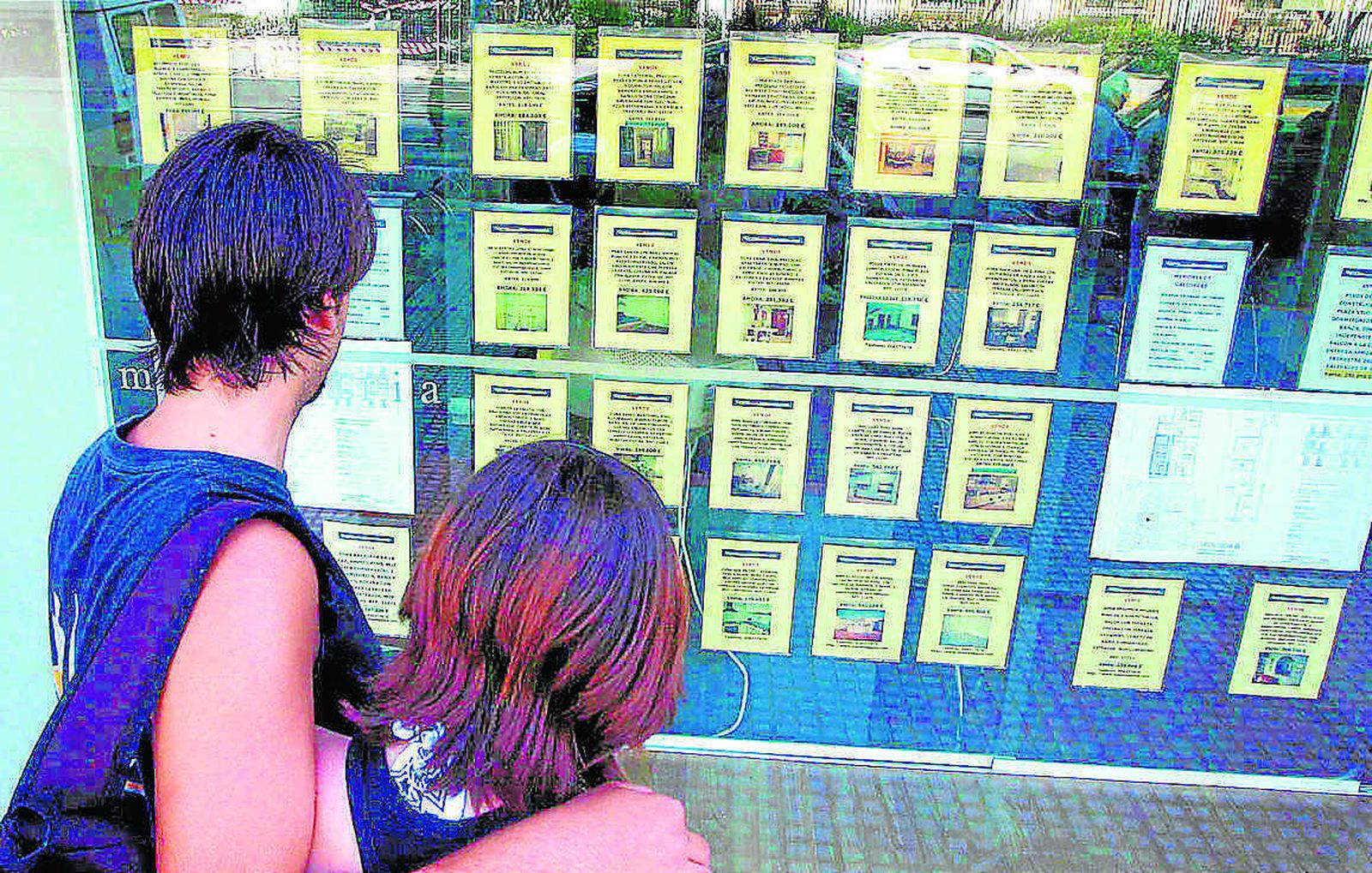 Una pareja observa anuncios de venta y alquiler de inmuebles.