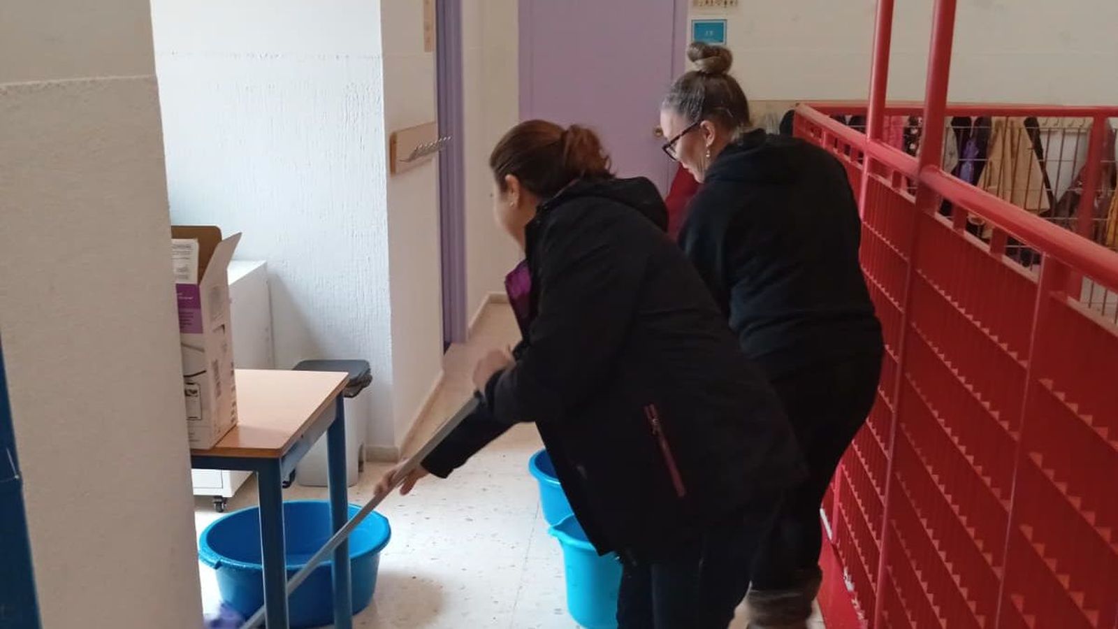 Dos madres secando el agua que entra en el centro