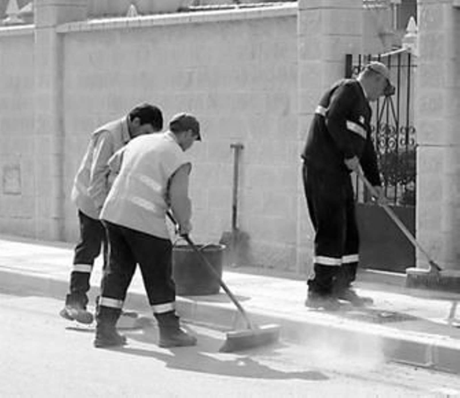 Varios operarios de limpieza adecentan la calle.