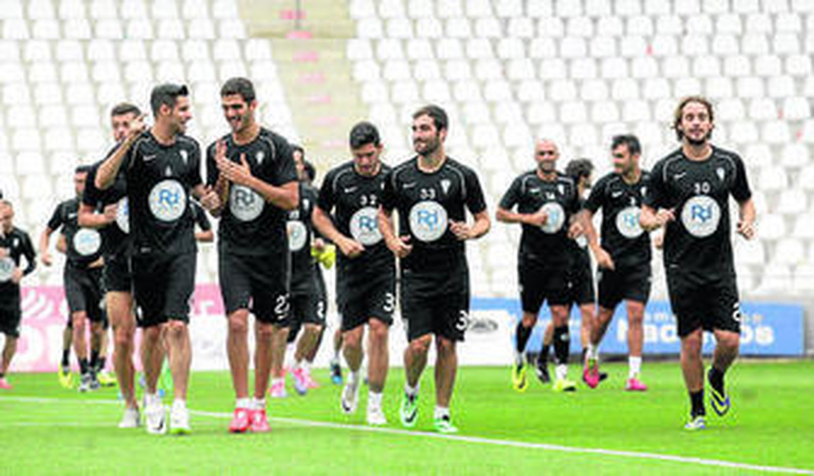 Los jugadores hacen carrera sobre el verde del estadio.