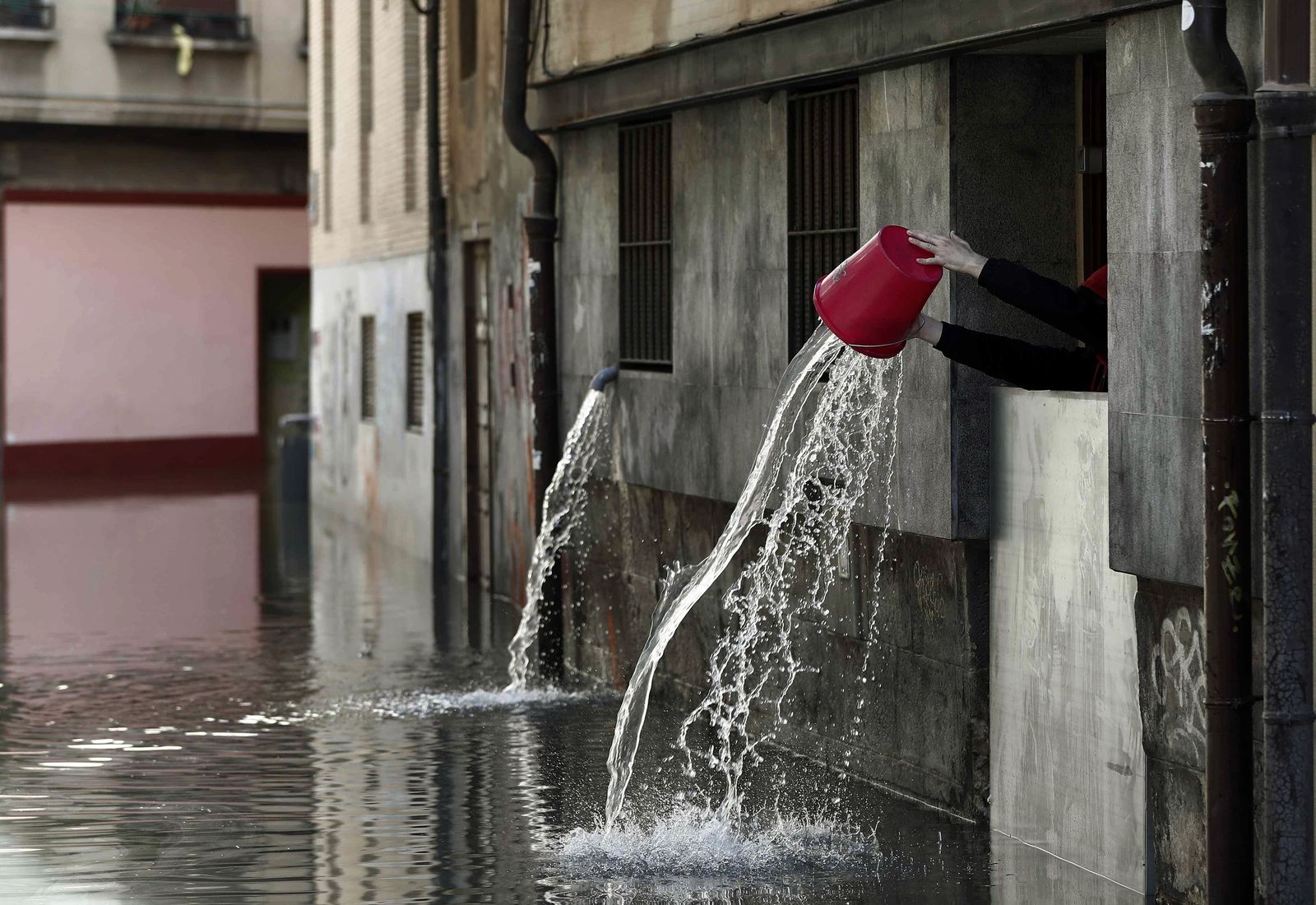Un vecino achica ayer agua por la ventana recogida de la cocina de un restaurante de Tudela (Navarra).