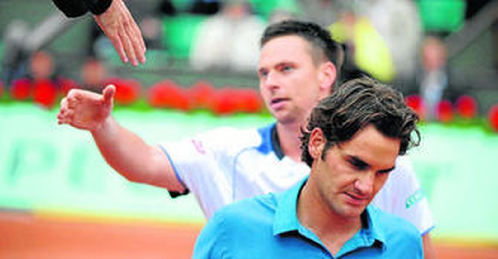 Roger Federer se marcha cabizbajo, mientras Robin Soderling saluda al juez de silla.