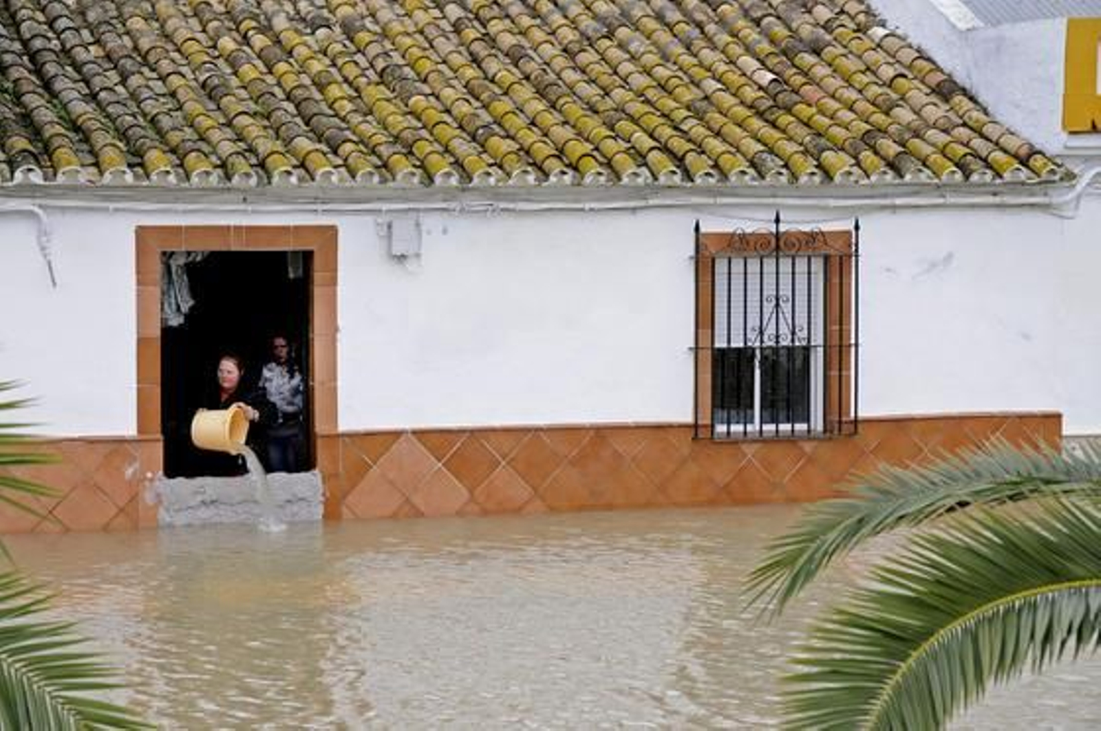 Una mujer achica el agua que inunda su casa con un cubo (Tocina).

Foto: Juan Carlos Vázquez