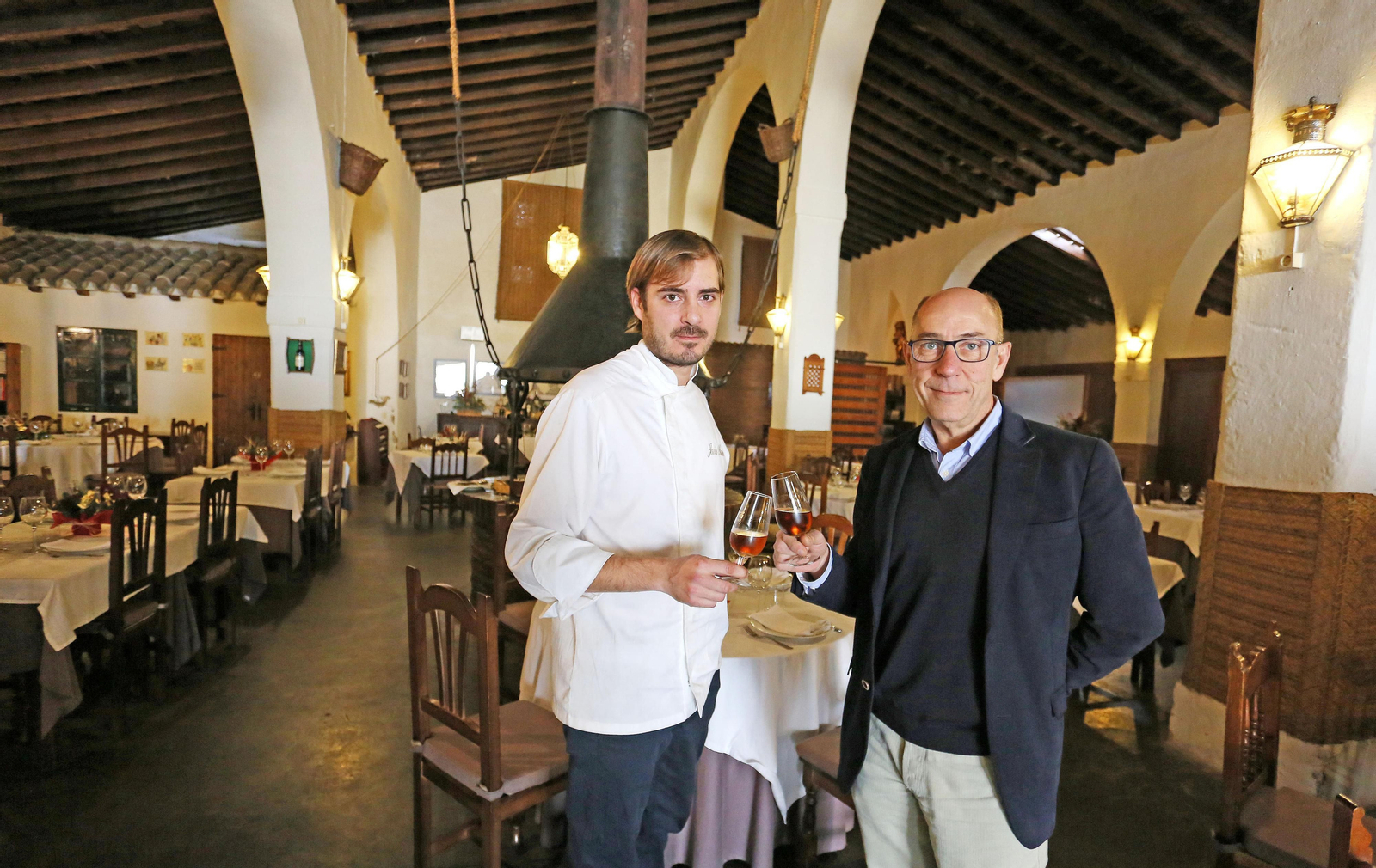 Javier Muñoz, a la izquierda, brinda con jerez con su padre en 'La Carboná'.
