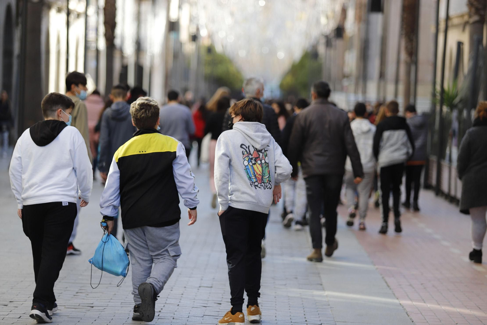 Un grupo de adolescentes pasea con sus mascarillas por la capital onubense.