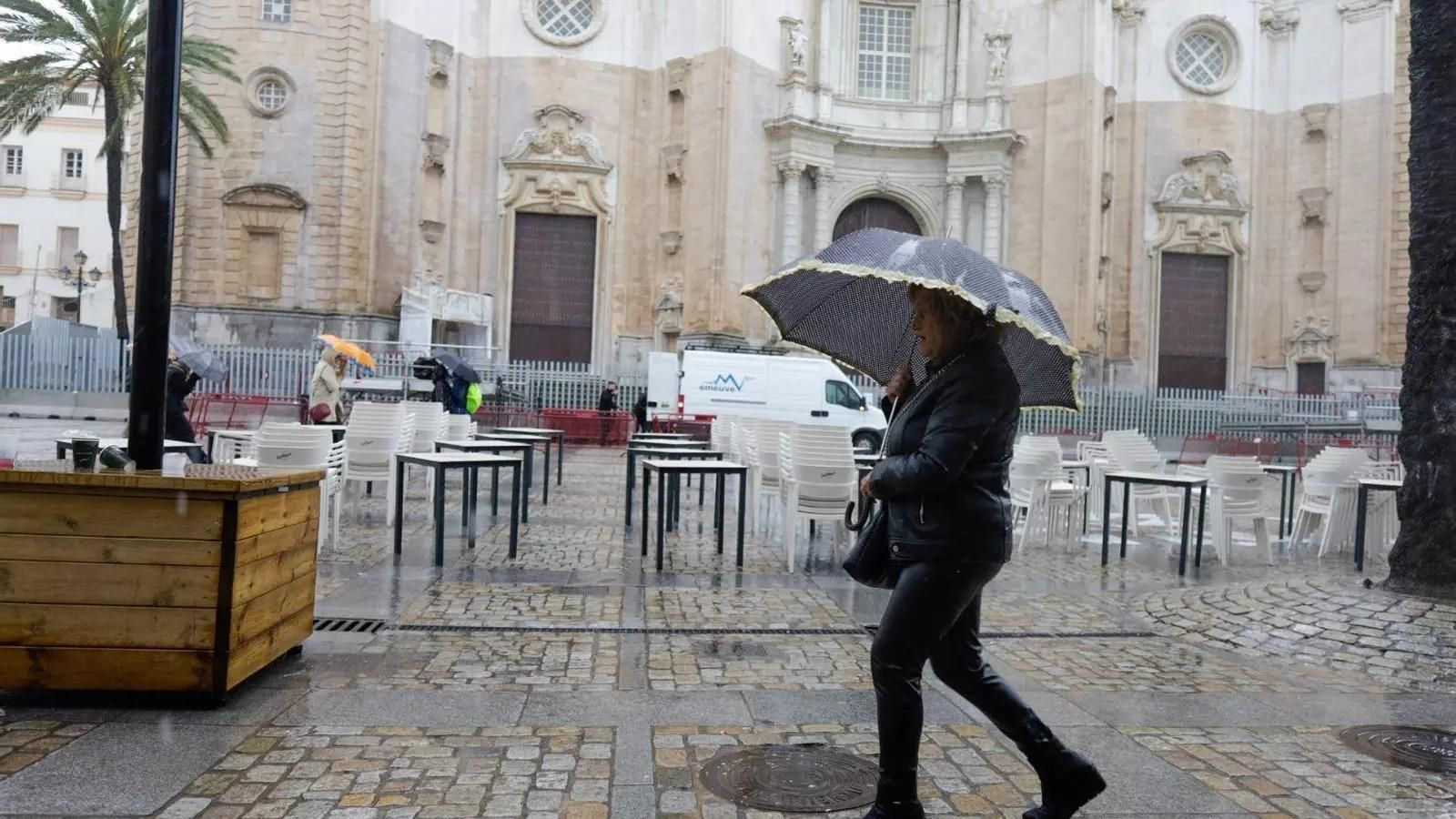 Una mujer pasea por la Catedral de Cádiz en un día lluvioso