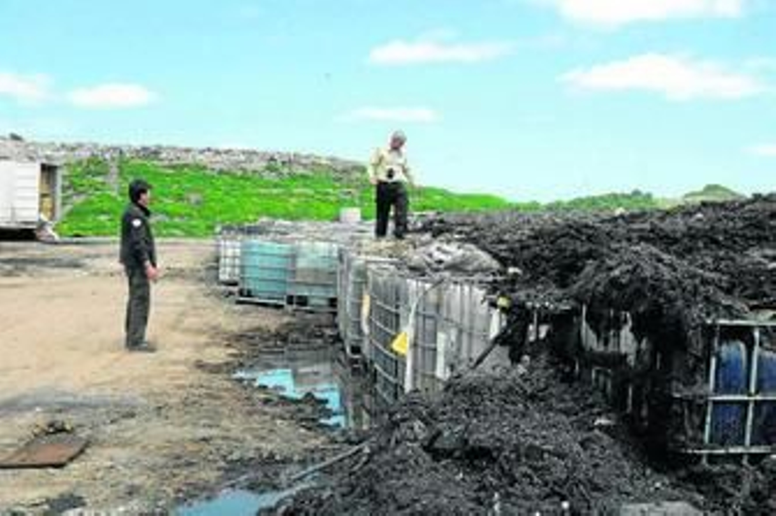 Dos técnicos inspeccionan los bidones de Gamasur.