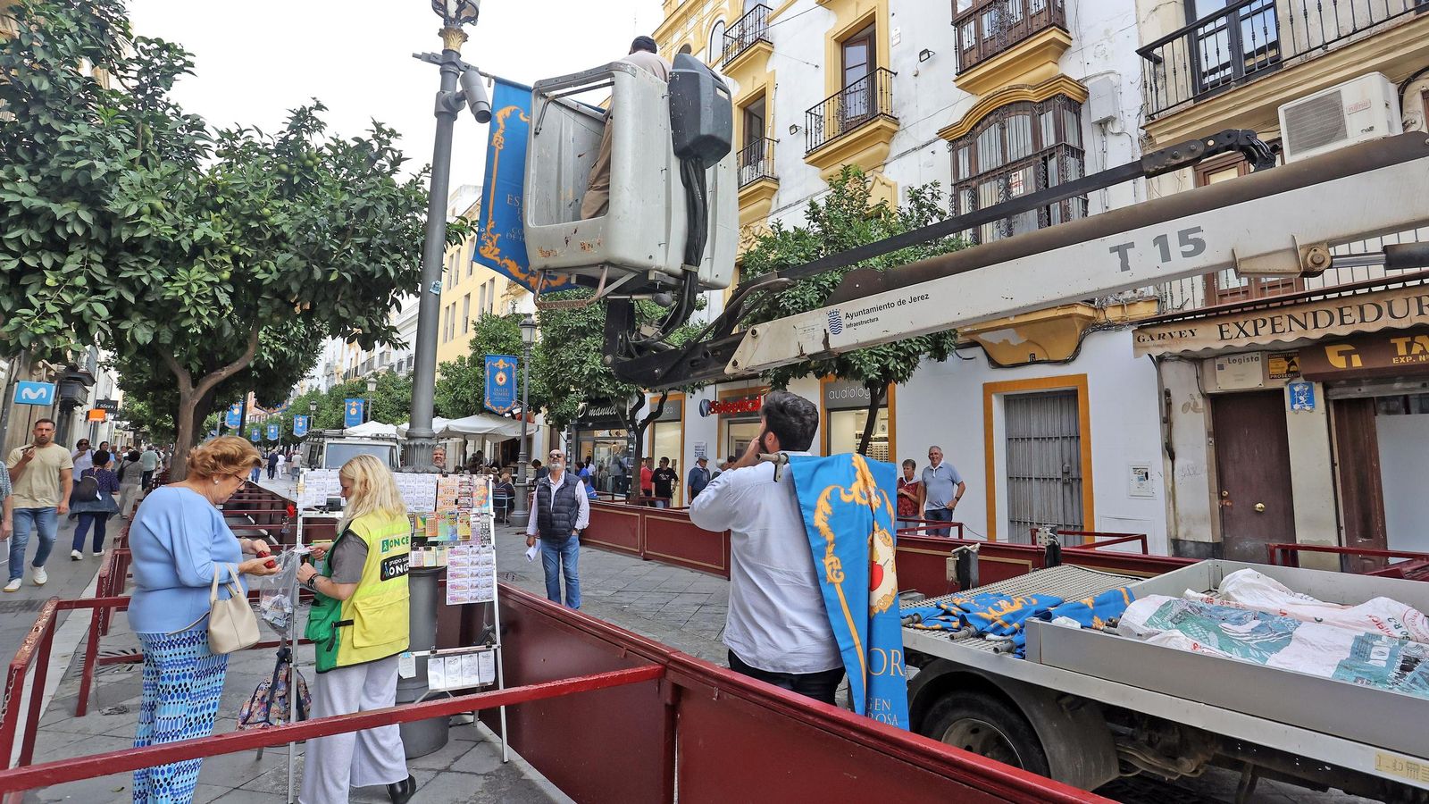 Operarios municipales colocando unas banderolas en la calle Larga para la Magna Mariana.