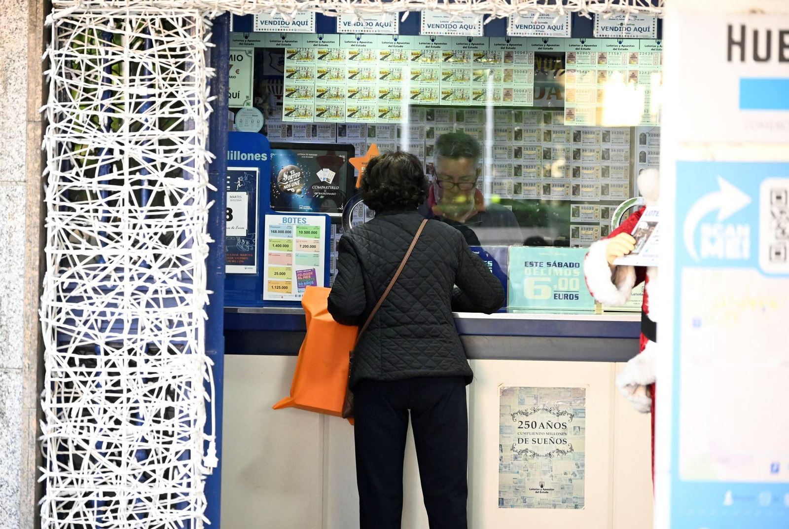 Una persona compra un décimo de Navidad en la administración de El Punto en Huelva.