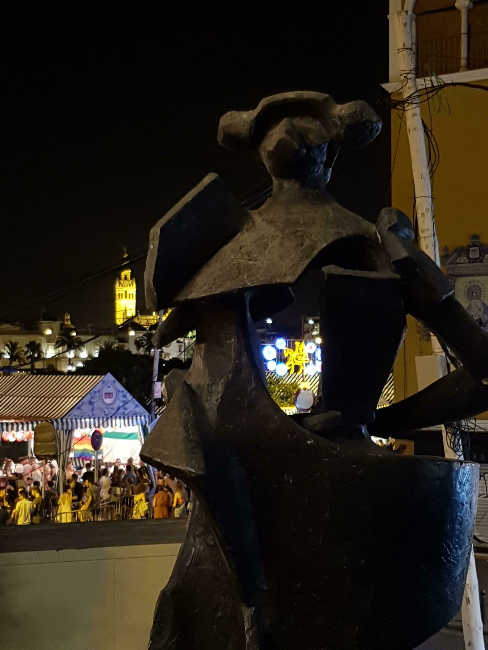 Una flamenca a la grupa se observa a través de la estatua de Juan Belmonte.