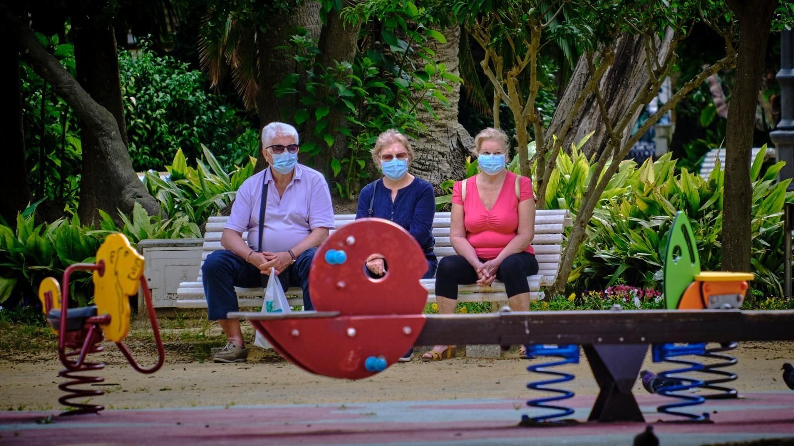 Tres personas con sus mascarillas sentadas en el parque Genovés.