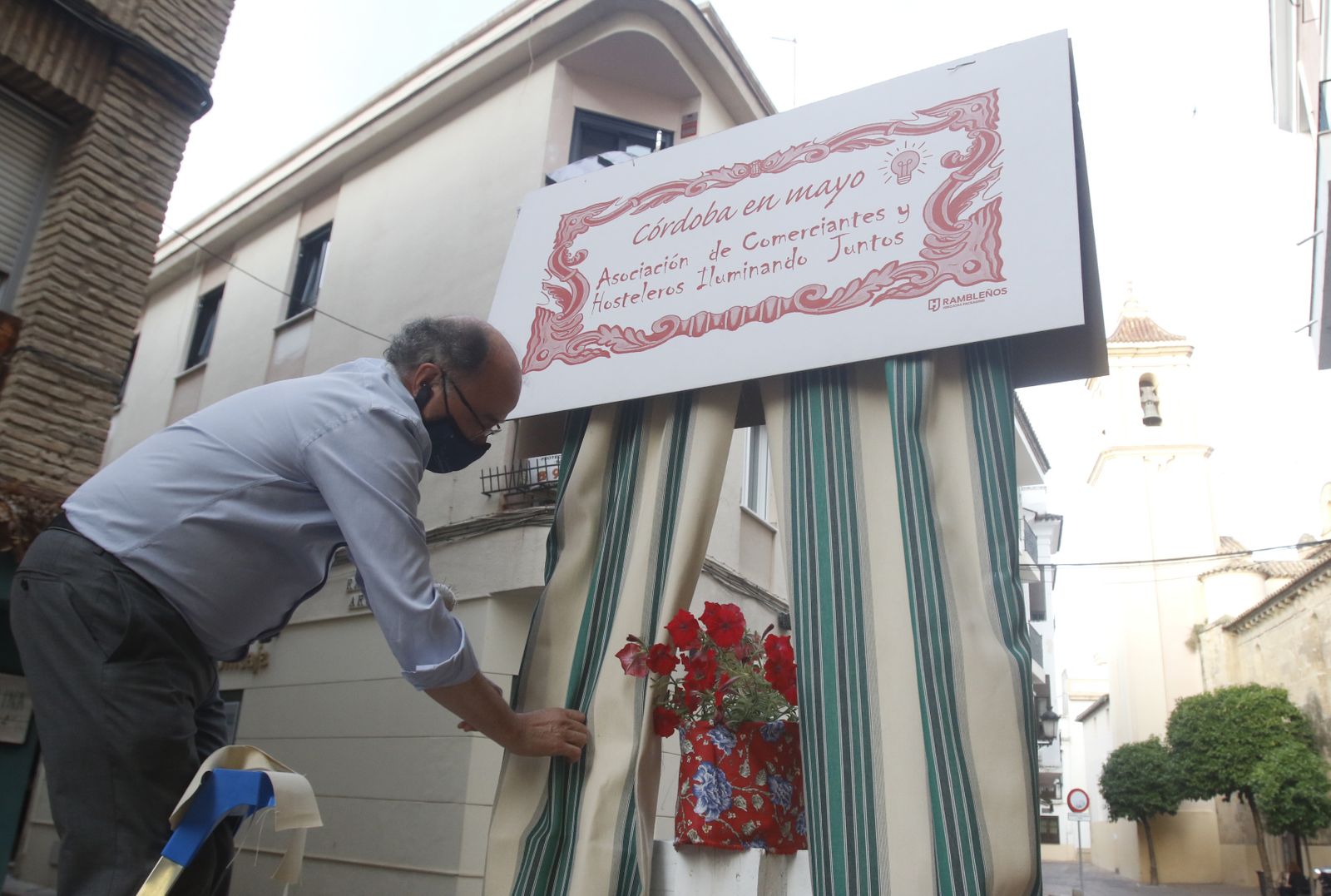 Pedro Jiménez coloca la cortina de feria de la portada de la Asociación Iluminando.