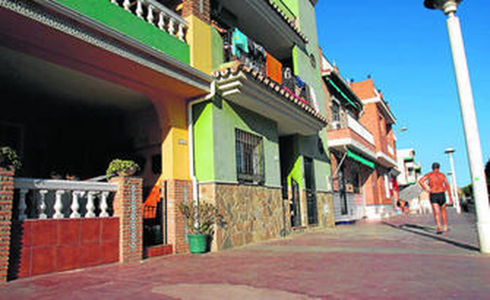 Un bañista pasa junto a algunas de las casas de El Palo, situadas en dominio marítimo-terrestre.