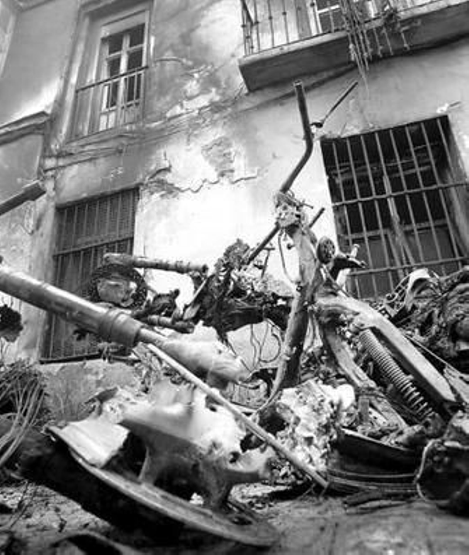 Uno de los vehículos que resultó calcinado, ante la fachada dañada de una de las fincas.