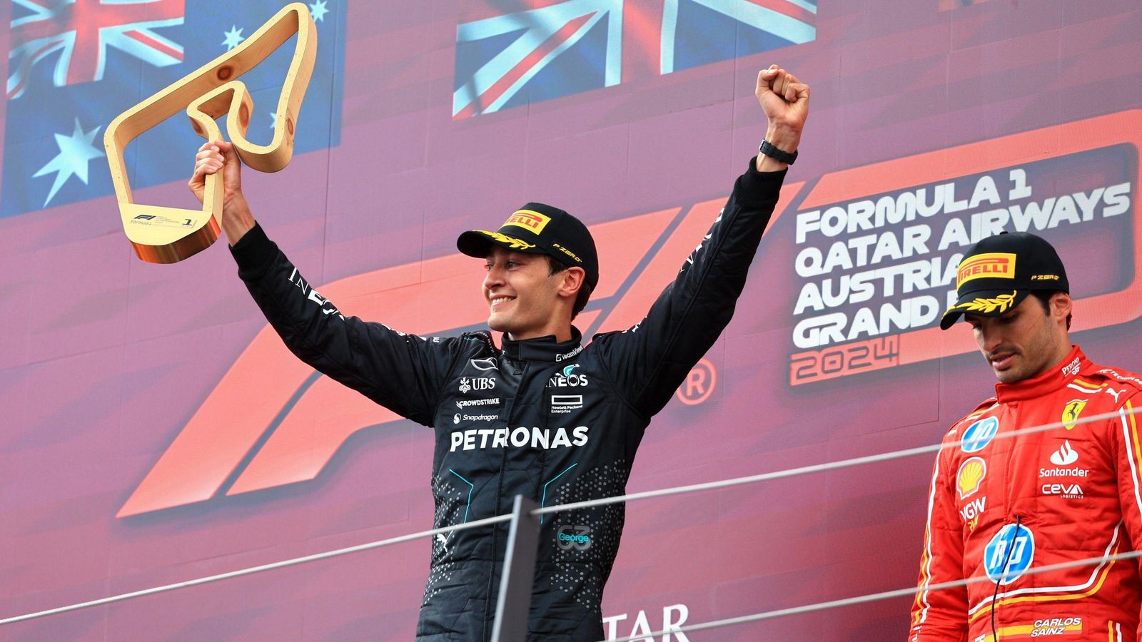 George Russel celebra en el podio cerca de Carlos Sainz, tercero en Spielberg. George Russel celebra en el podio cerca de Carlos Sainz, tercero en Spielberg.