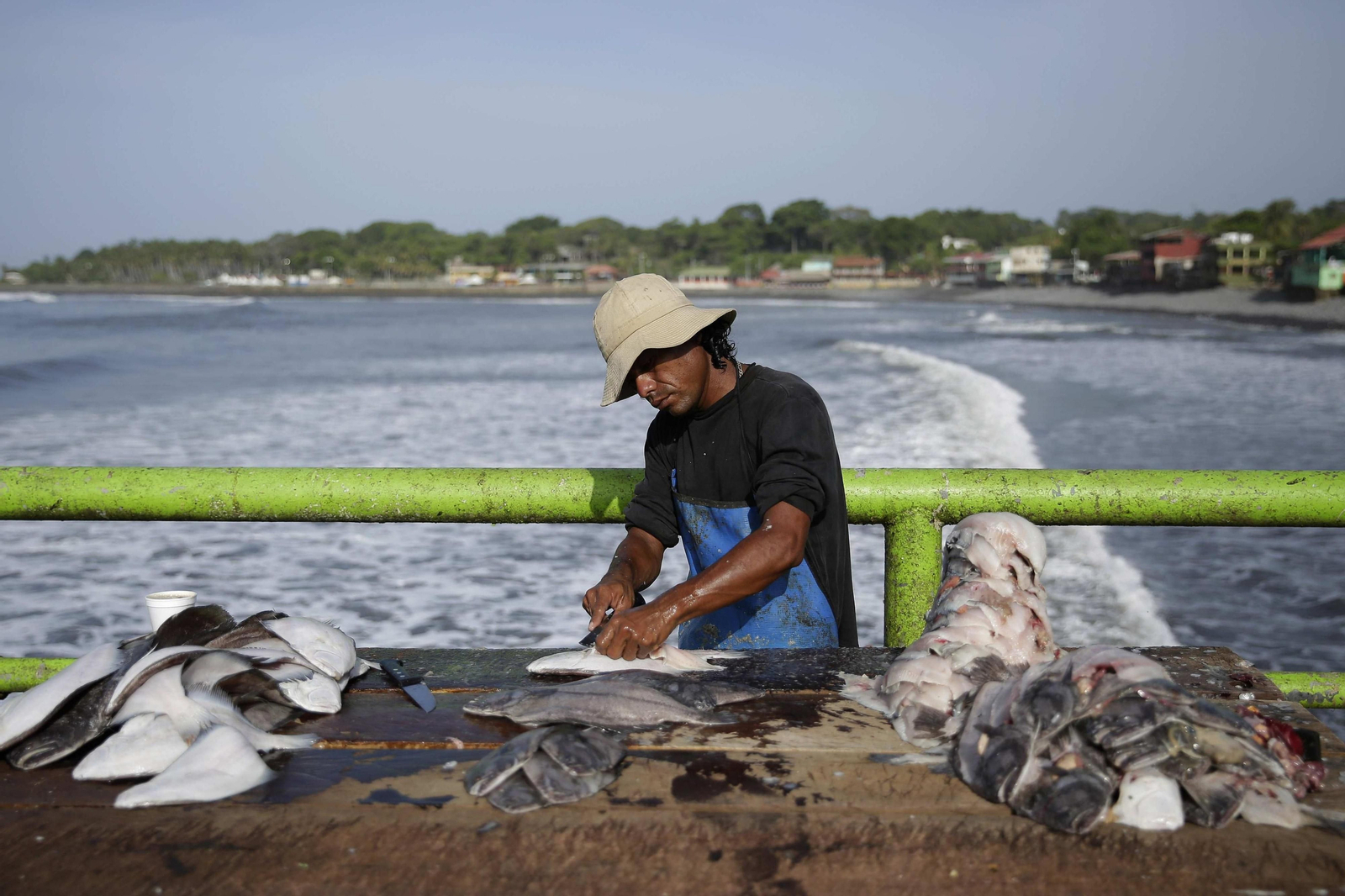 Un pescador limpia una pieza a bordo de un barco.